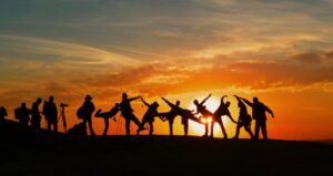 Groupe de personnes se découpant sur un coucher de soleil vibrant, mettant en valeur l'unité et la joie.