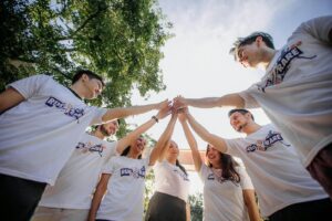 Un groupe de jeunes adultes en chemises blanches partageant un moment de joie en équipe à l'extérieur.