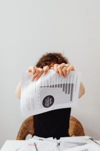 Une personne déchire un rapport financier par frustration, symbolisant le stress au travail.