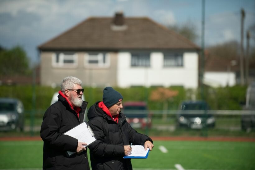 A couple of men standing next to each other on a field