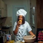 a woman in a chef's outfit is eating a doughnut