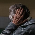 an older woman covering her face with her hands