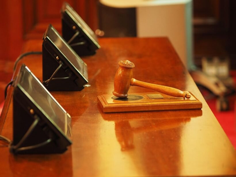 Marteau de juge en bois sur un bureau avec microphones, dans une salle d'audience
