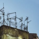 Des antennes TV métalliques fixées sur un toit usé sous un ciel bleu