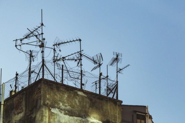 Des antennes TV métalliques fixées sur un toit usé sous un ciel bleu