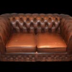 Canapé Chesterfield en cuir marron, capitonnage, deux coussins, fond noir