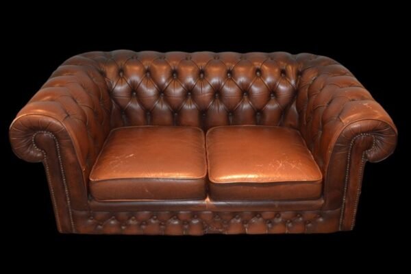 Canapé Chesterfield en cuir marron, capitonnage, deux coussins, fond noir