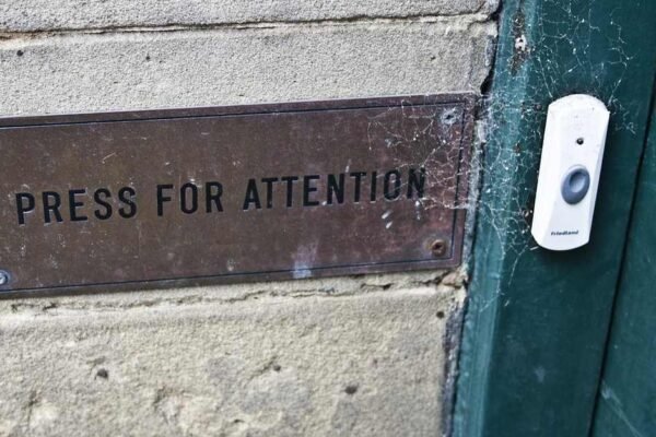 Plaque métallique sur mur en béton à côté d'une porte verte avec bouton
