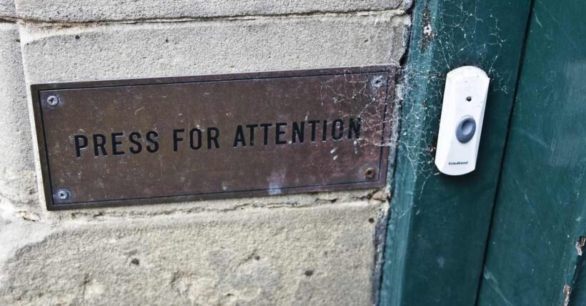 Plaque métallique sur mur en béton à côté d'une porte verte avec bouton