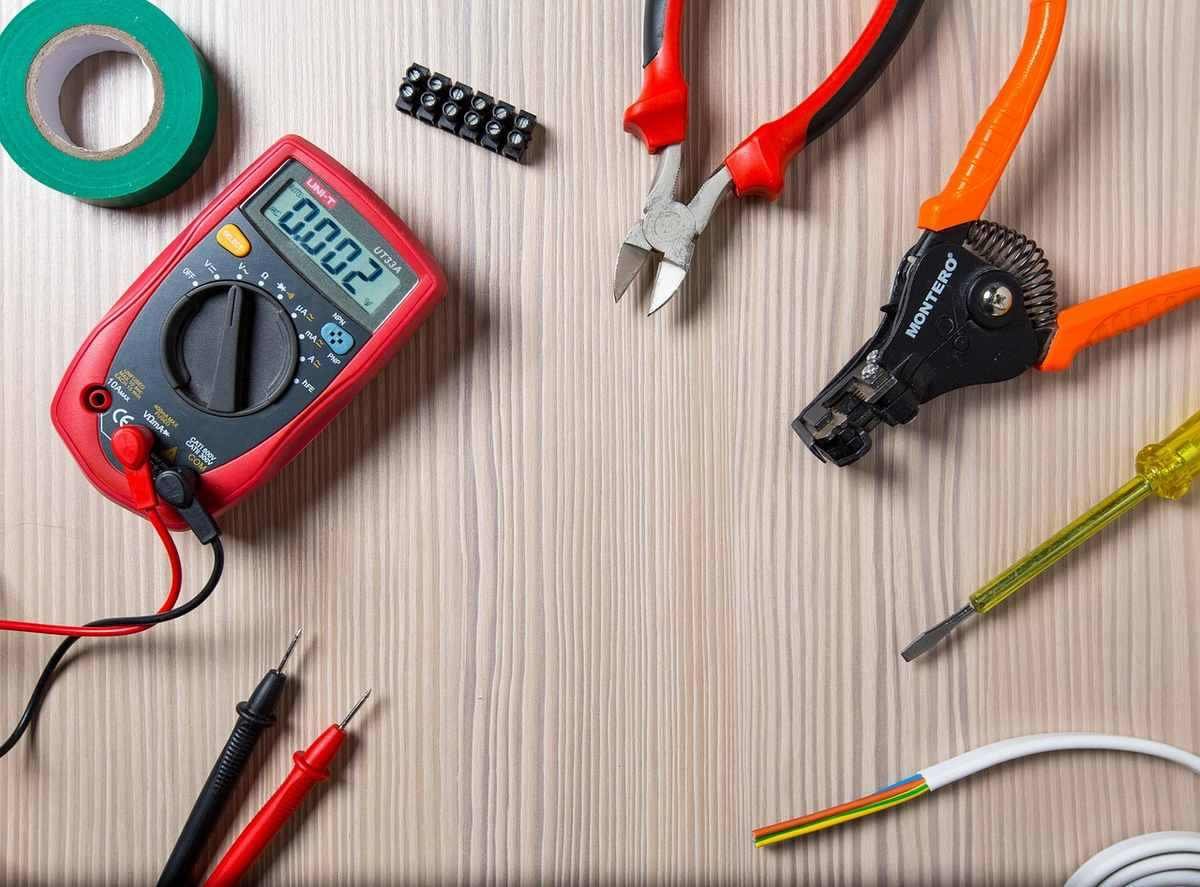 Outils de bricolage sur une table, incluant un multimètre, des pinces et un tournevis
